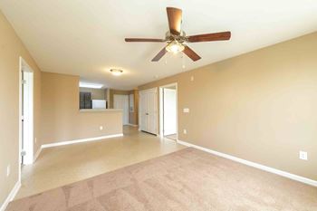 A spacious room with a ceiling fan and carpeted floor.